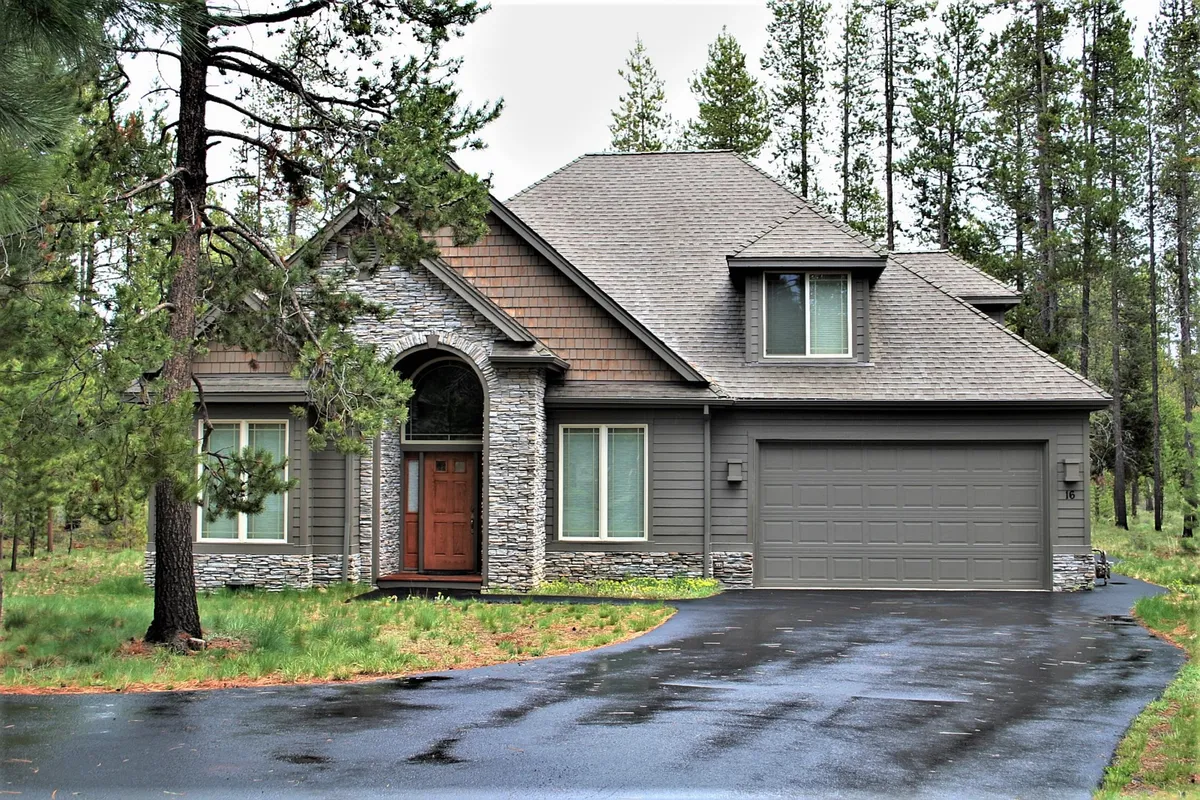 This image shows the charming exterior of Poplar 16, complete with a welcoming stone archway, a wooden front door, and garage. The lush greenery and pathway suggest a peaceful, private retreat within Sunriver Resort.