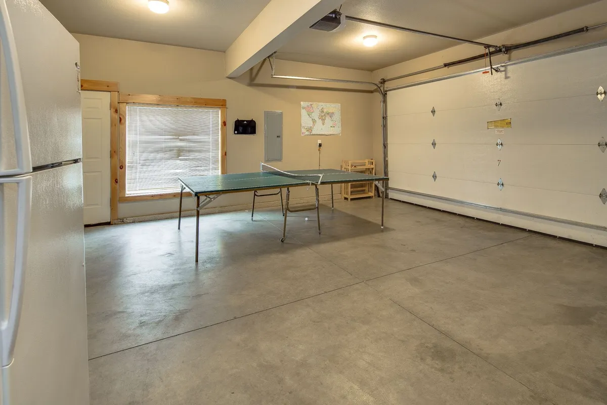 A casual shot of the garage’s ping pong table, with a refrigerator and a map on the wall providing a laid-back, clubhouse feel. The image suggests friendly competition and relaxed hangouts, with space for storing snacks and drinks—perfect for long game nights. The map on the wall subtly hints at the adventurous spirit of Sunriver, tying in the availability of bikes for exploration.