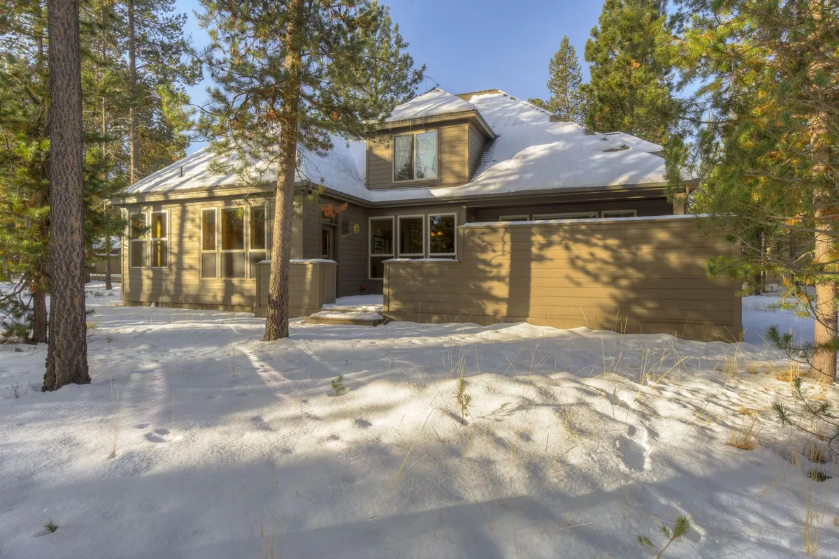 The home’s exterior framed by snow and trees, with ample space for outdoor activities. The scene conveys both the proximity to nature and the inviting warmth of the home after winter excursions.