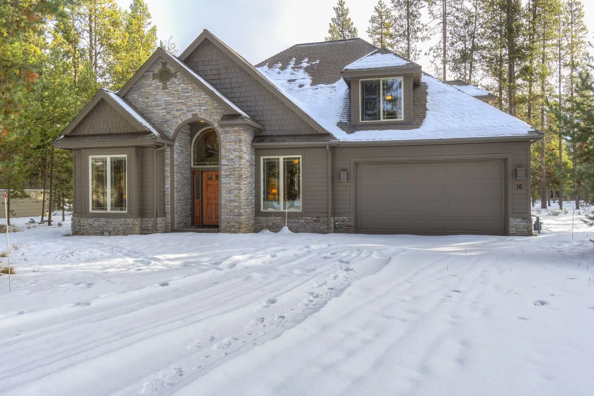 A picturesque winter scene at Poplar 16, with its stone facade, wooden front door, large windows, and a snow-covered landscape. The inviting look highlights the cozy possibilities for winter fun and holiday gatherings.